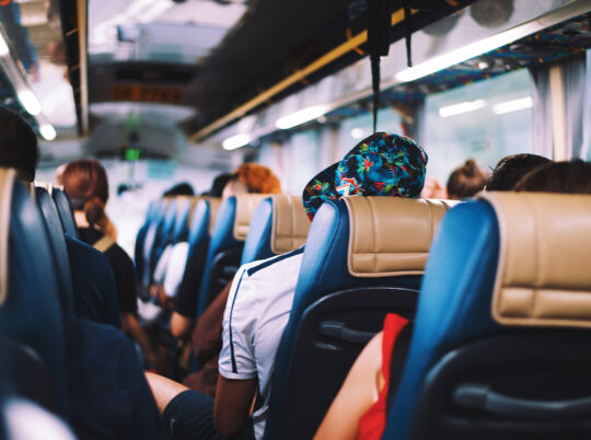 A back-to-front shot of a bus full of people in blue and tan seats