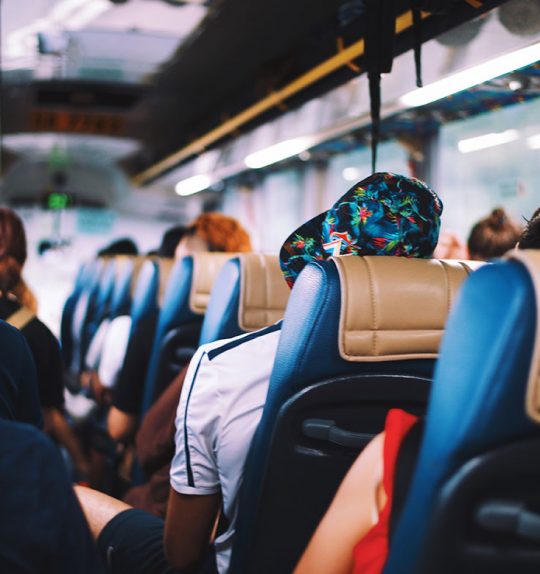 A back-to-front shot of a bus full of people in blue and tan seats